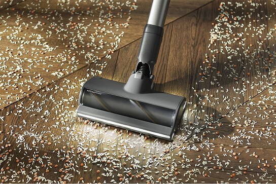 L'aspirateur balai aspire la saleté sur un parquet.