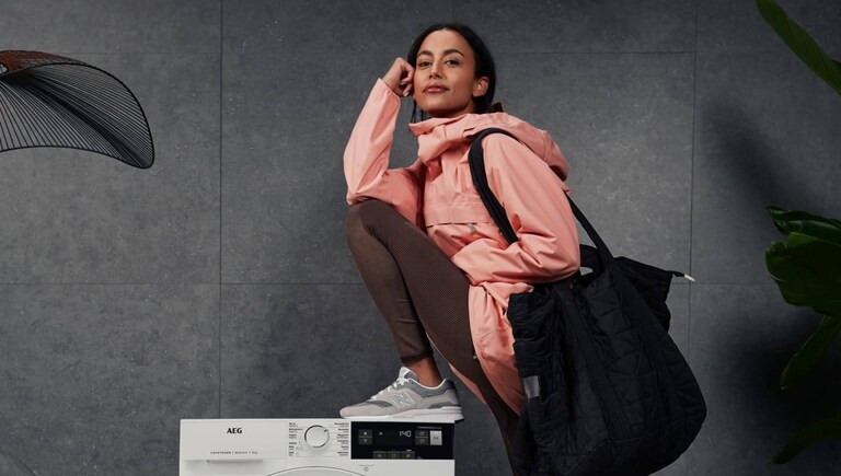 Femme appuyée contre un lave-linge séchant AEG.
